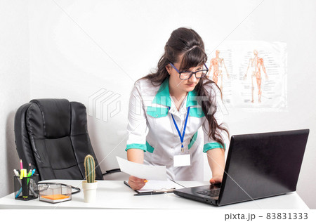 beautiful young girl the doctor enters the results of the analyzes into the electronic card of the patient. E-health concept. Copy space for text 83831333