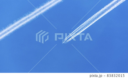 Two engined airplane during flight in high altitude with condensation trails 83832015