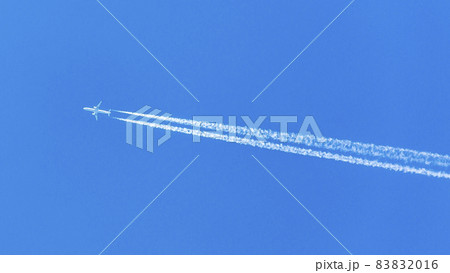 Two engined airplane during flight in high altitude with condensation trails 83832016