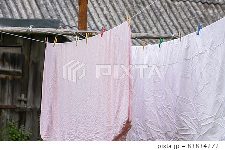 Freshly washed bed linen hanging on the rope outdoors. 83834272
