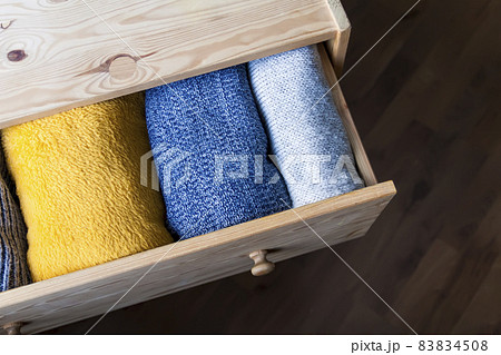 Open wooden dresser drawer with warm woolen clothes. Home vertical storage. Wardrobe organizing. Open wooden dresser drawer with warm woolen clothes. Home vertical storage. Wardrobe organizing. 83834508