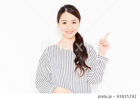 指でポイントを指し示すカジュアルな服装の女性 83835292