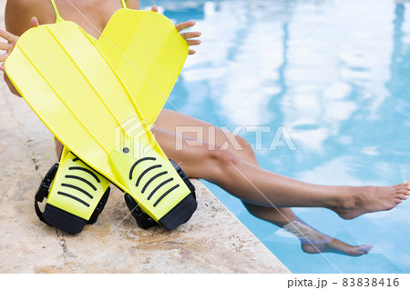 Female hands holding flippers near swimming pool. Concept of summer holidays. Female hands holding flippers near swimming pool. Concept of summer holidays. 83838416