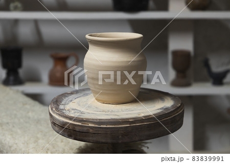 White clay pot stands on a pottery wheel, closeup White clay pot stands on a pottery wheel, closeup 83839991