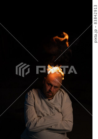 Bald man in a straitjacket with a burning head on a dark background. Bald man in a straitjacket with a burning head on a dark background. 83842913