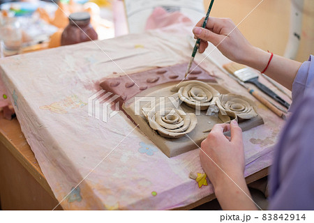 A woman is painting a handmade ceramic craft. 83842914