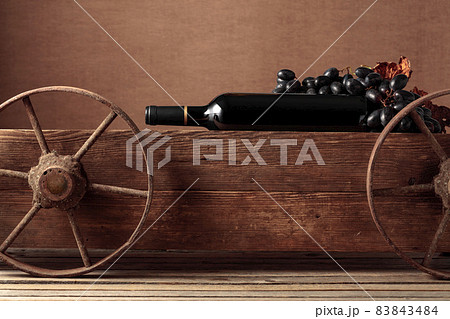 Old wooden cart with bottle of red wine and grapes. Old wooden cart with bottle of red wine and grapes. 83843484