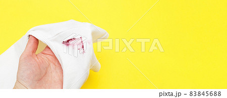 female hand holding white shirt with red lipstick stain on yellow background 83845688