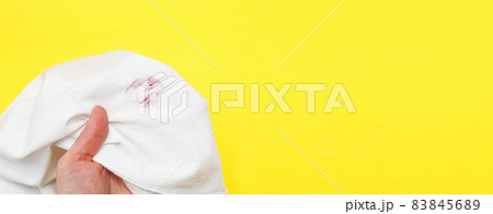 Woman holding a white shirt with red kiss lipstick on a yellow background Woman holding a white shirt with red kiss lipstick on a yellow background 83845689