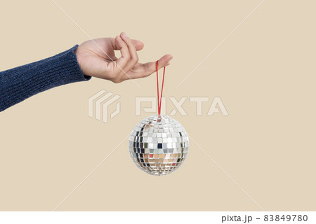 Woman holding silver christmas disco ball isolated on flesh color background. 83849780