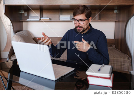 Focused man sitting at desk watching webinar video course Focused man sitting at desk watching webinar video course 83850580