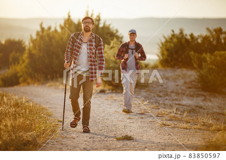 two men hikers enjoy a walk in nature, sunset time in summer two men hikers enjoy a walk in nature, sunset time in summer 83850597