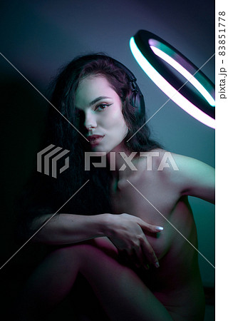 Emotional studio portrait young woman in a wireless headphones with ring flash effect. Round LED Circle Lamp. Emotional studio portrait young woman in a wireless headphones with ring flash effect. Round LED Circle Lamp. 83851778