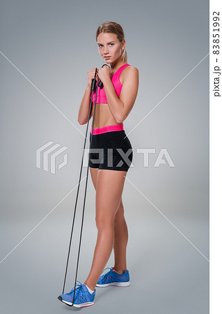Full length image of a pretty fitness woman doing exercise with skipping rope over gray background Full length image of a pretty fitness woman doing exercise with skipping rope over gray background 83851992