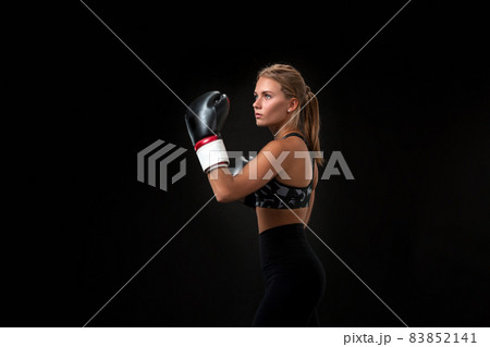 Beautiful female athlete in boxing gloves, in the studio on a black background. Beautiful female athlete in boxing gloves, in the studio on a black background. 83852141