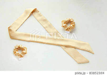 golden silk scrunchy flat lay on white. Hairdressing tools and accessories. luxury ladyes hair scarf 83852304