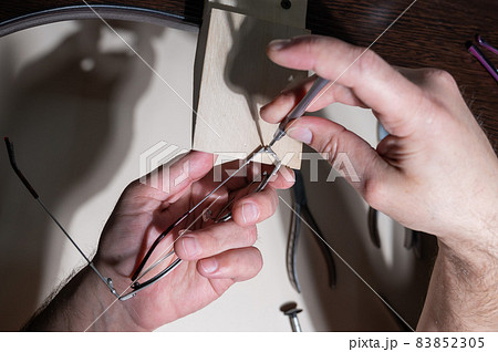 Optical technician fixing glasses. Close-up of male hands with screwdriver and goggles frame. 83852305