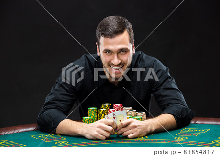 Happy poker player winning and holding a pair of aces Happy poker player winning and holding a pair of aces 83854817