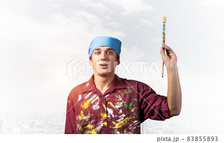 Handsome young painter artist pointing upwards Handsome young painter artist pointing upwards 83855893