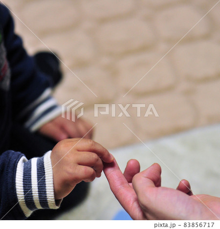 母親の人差し指に触れようとしている幼子の小さな指 83856717