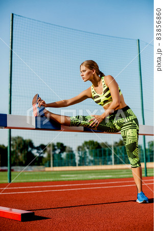 Young, beautiful girl athlete in sportswear doing warm-up at the stadium Young, beautiful girl athlete in sportswear doing warm-up at the stadium 83856860