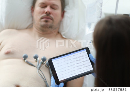 Doctor taking cardiogram to sick patient man on digital tablet in clinic closeup 83857681
