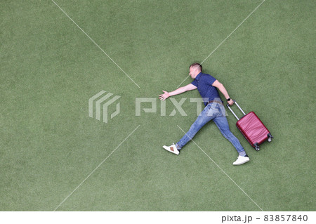 Young man with suitcase walking on green grass top view Young man with suitcase walking on green grass top view 83857840