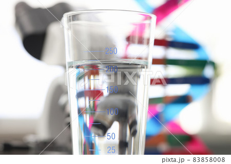 Glass of water standing near dna molecule mockup and microscope in laboratory closeup Glass of water standing near dna molecule mockup and microscope in laboratory closeup 83858008