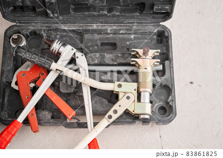 Tools of plumber for clamps the connectors on the pipe. connection heating pipes to white Radiator in a new apartment under construction. Tools of plumber for clamps the connectors on the pipe. connection heating pipes to white Radiator in a new apartment under construction. 83861825