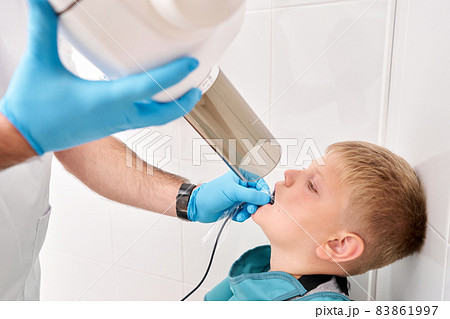 Radiographer taking teeth radiography to a boy using digital x-ray machine in pediatric dental clinic. Dentist prepares boy for tooth x-ray image in dental clinic. Radiographer taking teeth radiography to a boy using digital x-ray machine in pediatric dental clinic. Dentist prepares boy for tooth x-ray image in dental clinic. 83861997