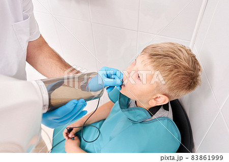 Radiographer taking teeth radiography to a boy using digital x-ray machine in pediatric dental clinic. Dentist prepares boy for tooth x-ray image in dental clinic. Radiographer taking teeth radiography to a boy using digital x-ray machine in pediatric dental clinic. Dentist prepares boy for tooth x-ray image in dental clinic. 83861999