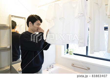 風呂場に干したシャツの匂いを嗅いで鼻をつまむ男性 風呂場に干したシャツの匂いを嗅いで鼻をつまむ男性 83863407