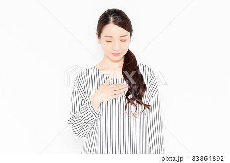 胸に手を当てるカジュアルな服装の女性 83864892