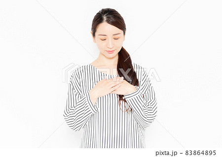 胸に手を当てるカジュアルな服装の女性 83864895
