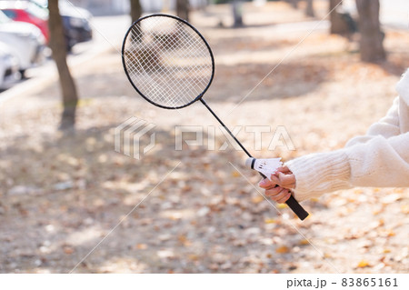 バドミントンのラケットを握る女性 落ち葉とバドミントンの写真素材