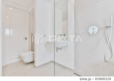 Minimalist bright bathroom with toilet, faucet and shower tall 83866326