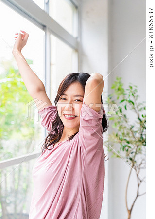 窓際に立って朝の光を浴びる気分爽快な女性 83866637