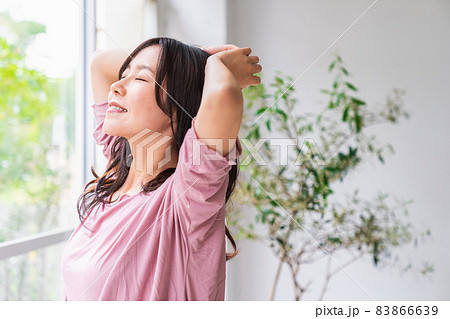 窓際に立って朝の光を浴びる気分爽快な女性 83866639