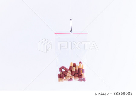 Colored Pills or Tablets Hanging in Small Ziplock Bag on a Fishing Hook Colored Pills or Tablets Hanging in Small Ziplock Bag on a Fishing Hook 83869005