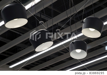 The ceiling is made of gray slats. Large black shades with white bulbs hang from the ceiling 83869295