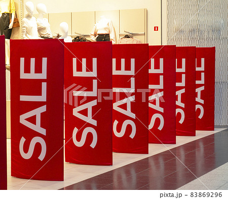 Sale in the store. Red posters with the inscription SALE at the entrance to the clothing department 83869296