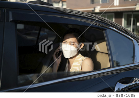 Young asian woman talking on mobile phone while sitting in a taxi. 83871688