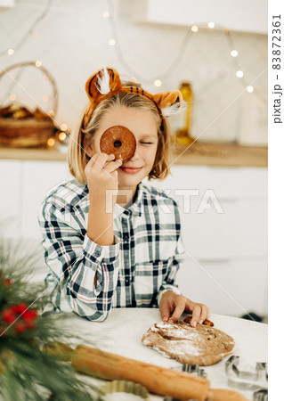 A cheerful girl hides her eyes behind Christmas cookies. Preparation for the holidays, Christmas spirit, Christmas treats 83872361