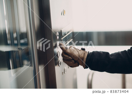 Close up of hand in glove forefinger pressing the button elevator during coronavirus pandemic covid-19 quarantine concept 83873404