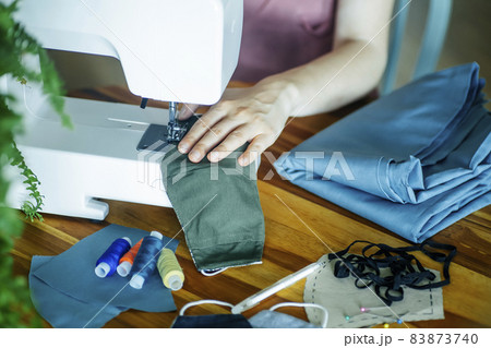 Mask sewing and making homemade covid mask concept. Sewing an individual antibacterial mask from colored fabric at home Mask sewing and making homemade covid mask concept. Sewing an individual antibacterial mask from colored fabric at home 83873740