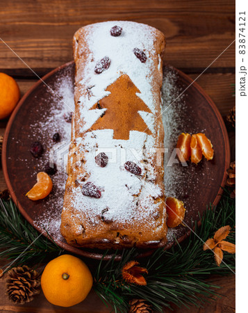 Christmas fruitcake powdered sugar tangerine fir tree festive decoration wooden background flat lay. Stollen cake loaf Christmas fruitcake powdered sugar tangerine fir tree festive decoration wooden background flat lay. Stollen cake loaf 83874121