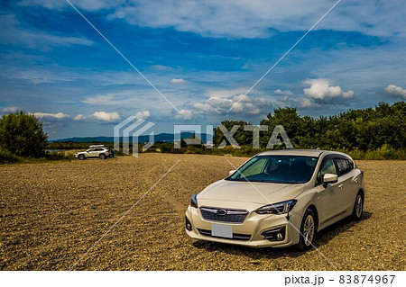 青空の下で河原の砂地に停まっている白い自動車 83874967