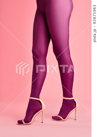 Legs of beautiful young woman in pink tights and stylish high heels shoes on pink background 83875963