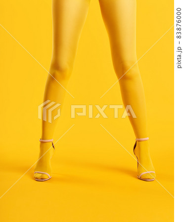 Long slim legs of young woman in yellow tights and stylish high heels shoes on yellow background Long slim legs of young woman in yellow tights and stylish high heels shoes on yellow background 83876000