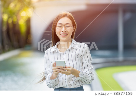 Portrait Asian business women adult smart woman standing looking camera with smartphone Portrait Asian business women adult smart woman standing looking camera with smartphone 83877159